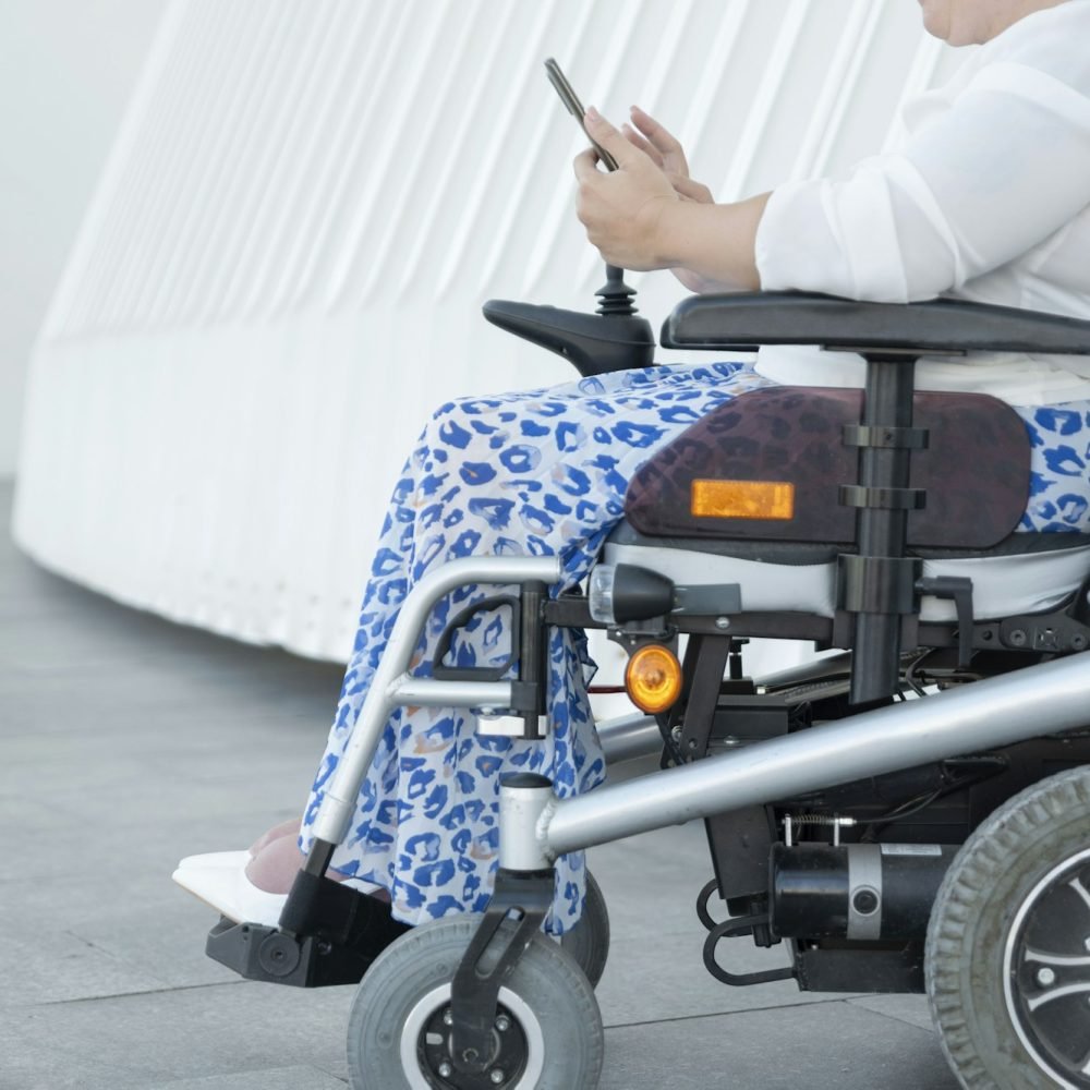 portrait of an unrecognizable woman with disability in a wheelchair looking at her smartphone