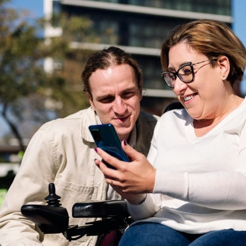 woman using wheelchair showing phone to a friend